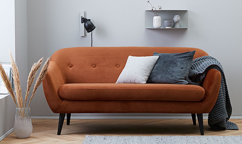 Stue med orange sofa med puder og en plaid