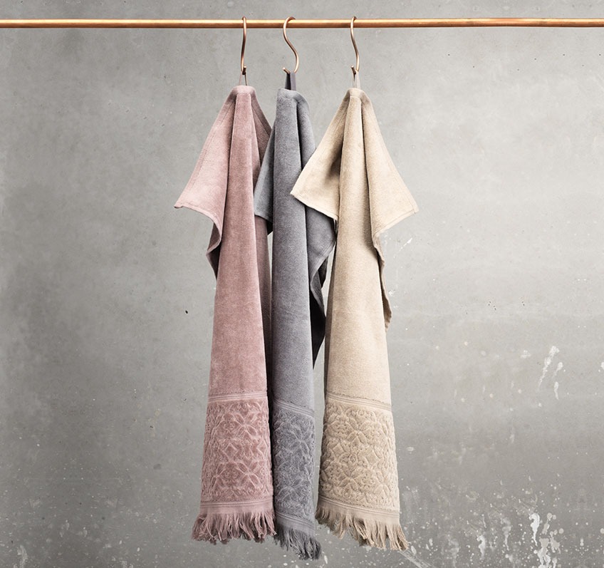 Taupe, sand and grey towel hanging from a rail 