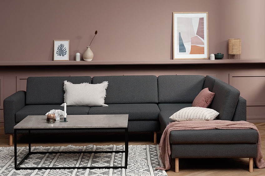 Grå sofa med chaiselong, pyntepuder og plaid i en stue