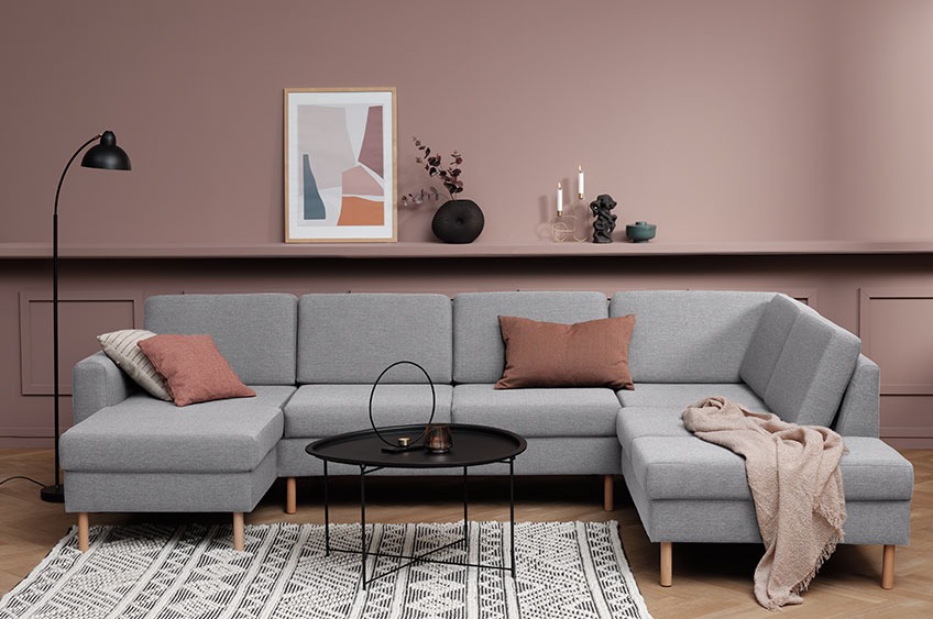 Stor grå hjørnesofa med pyntepder og plaid i en moderne stue