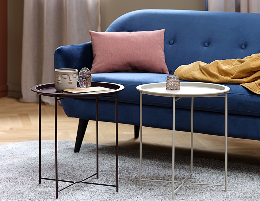 RANDERUP hjørneborde i rosa og lilla og EGEDAL sofa To små sofaborde foran en blå sofa