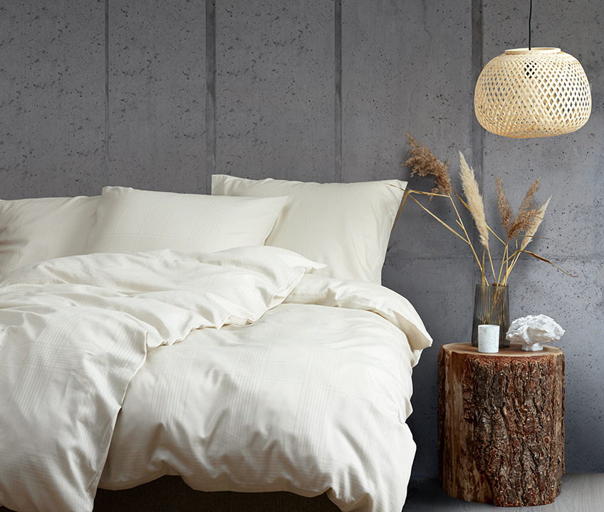 Elegant soveværelse med et roligt nordisk look og seng lavet med sandfarvet sengetøj