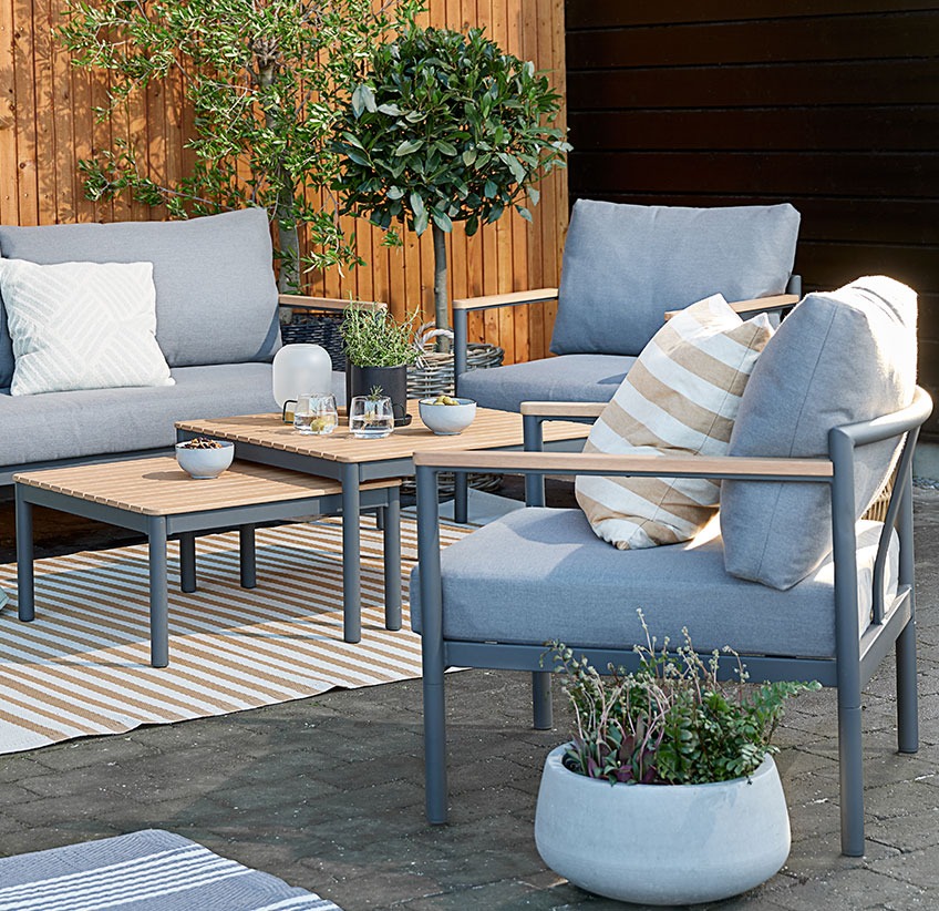 Have loungesæt med behagelige hynder på en terrasse med tæpper og krukker