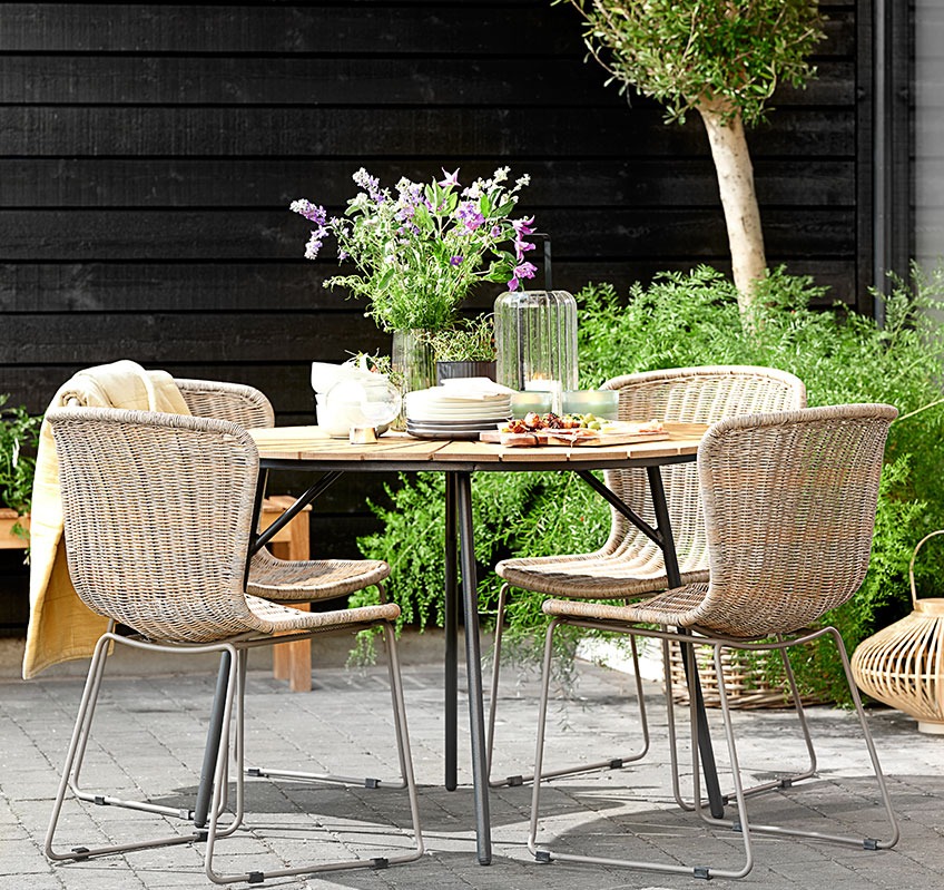 Fire HAJSTRUP stabelstole omkring det runde RANGSTRUP havebord Fire stabelstole omkring et rundt havebord på en terrasse