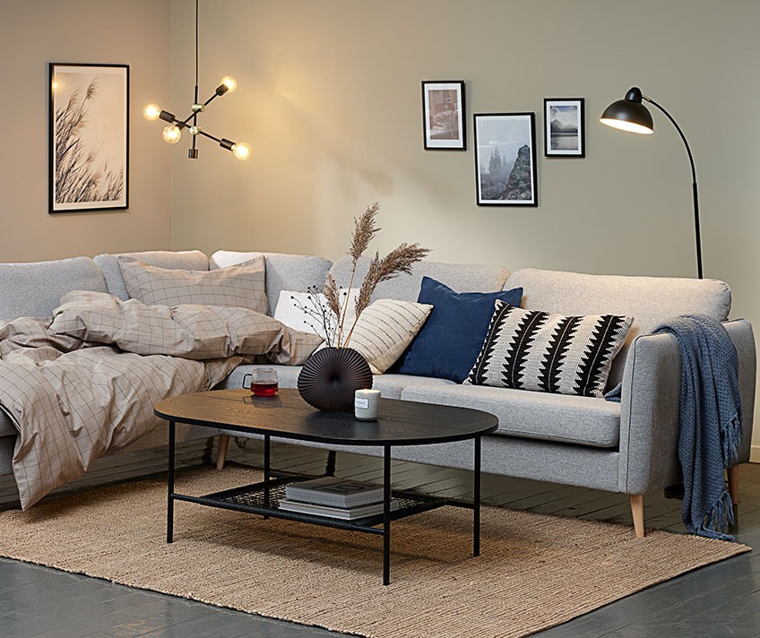Stue med polstrede møbler, tæppe på gulvet og pyntepuder og plaider, der alle medvirker til lyddæmpning