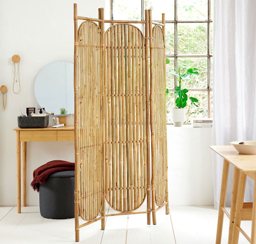 Bambus påklædningsskærm fungerer som en rumdeler mellem en spisestue og en soveplads
