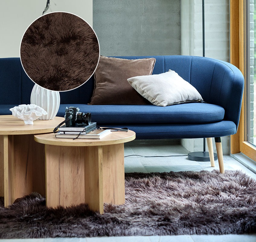 Stue med brunt tæppe i imiteret pels, blå sofa og runde sofaborde