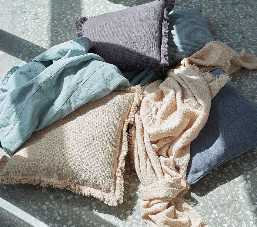 Blå VALMUE plaid, beige ROSE plaid og HORTENTIA og HORNFIOL puder Blå plaid, beige plaid og khaki og blå pyntepuder på gulvet