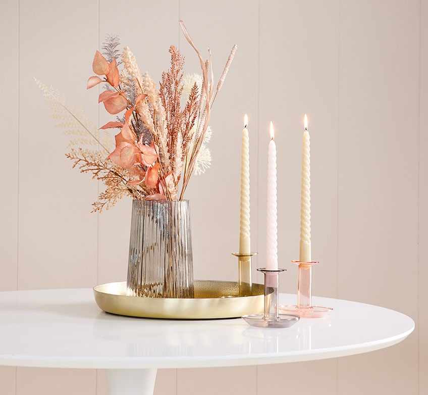 Bord med pyntebakke, vase med kunstige blomster og lysestager med stearinlys 
