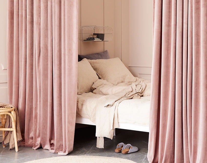 Rosa gardiner der adskiller et soveværelse fra en stor stue 