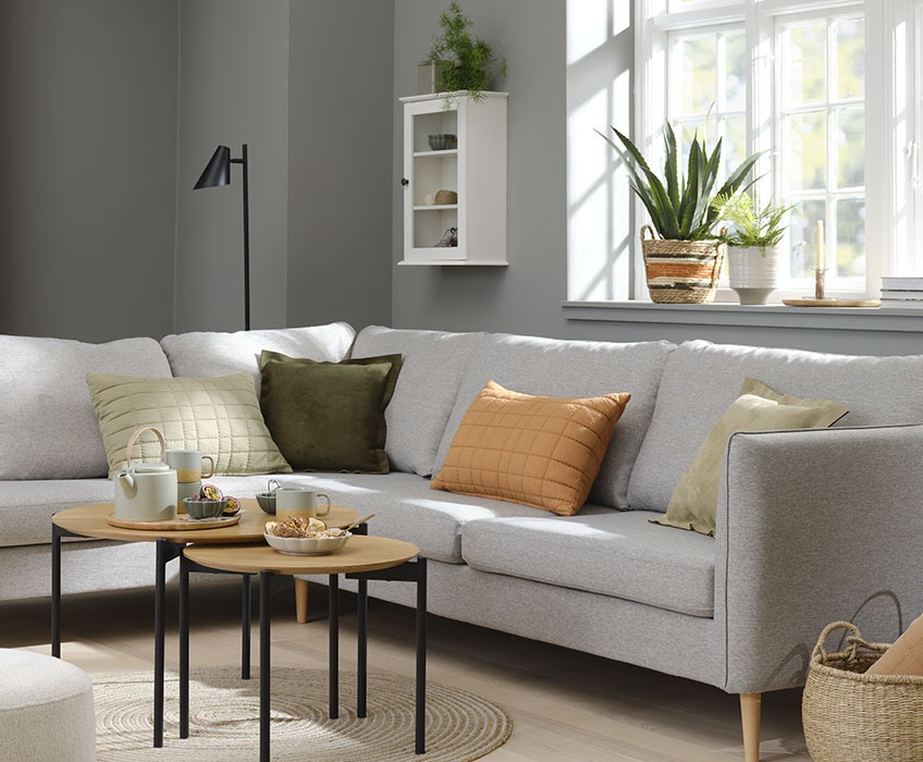 Stue med grå sofa og orange, grønne og beige puder 