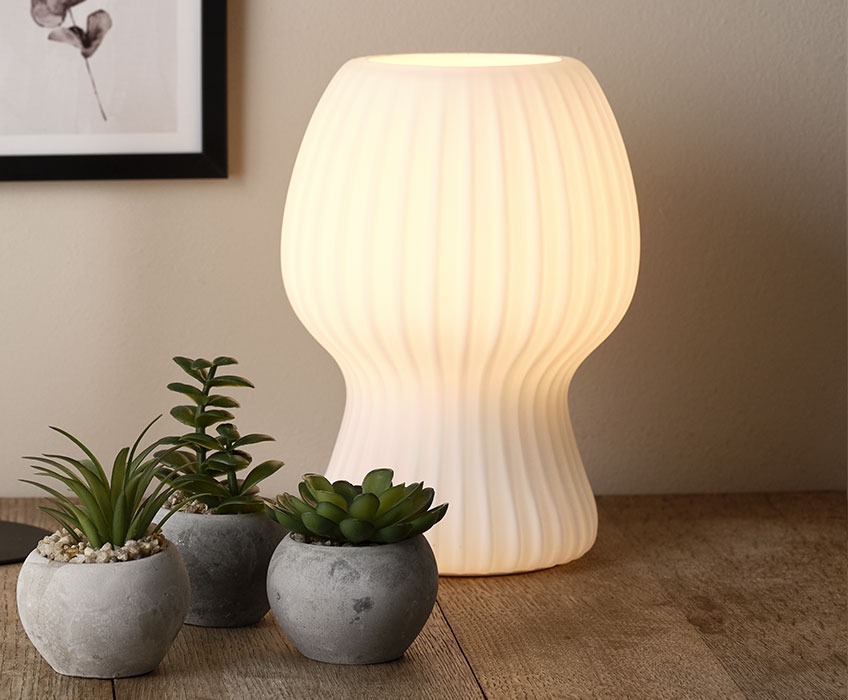 GERLUF bordlampe i glas og BROR kunstige planter Bordlampe lavet i riflet hvidt glas på et spisebord af træ