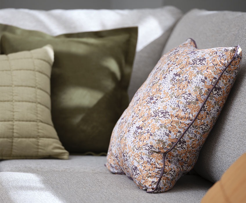 KAMILLE blomstret pyntepude og ALM grøn ruskindspude Grå sofa med blomstrede og grønne hynder