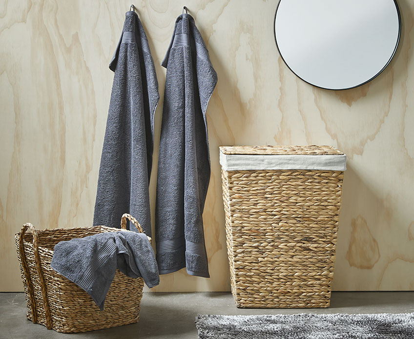 Vasketøjskurv, fletkurv og grå håndklæder på badeværelse