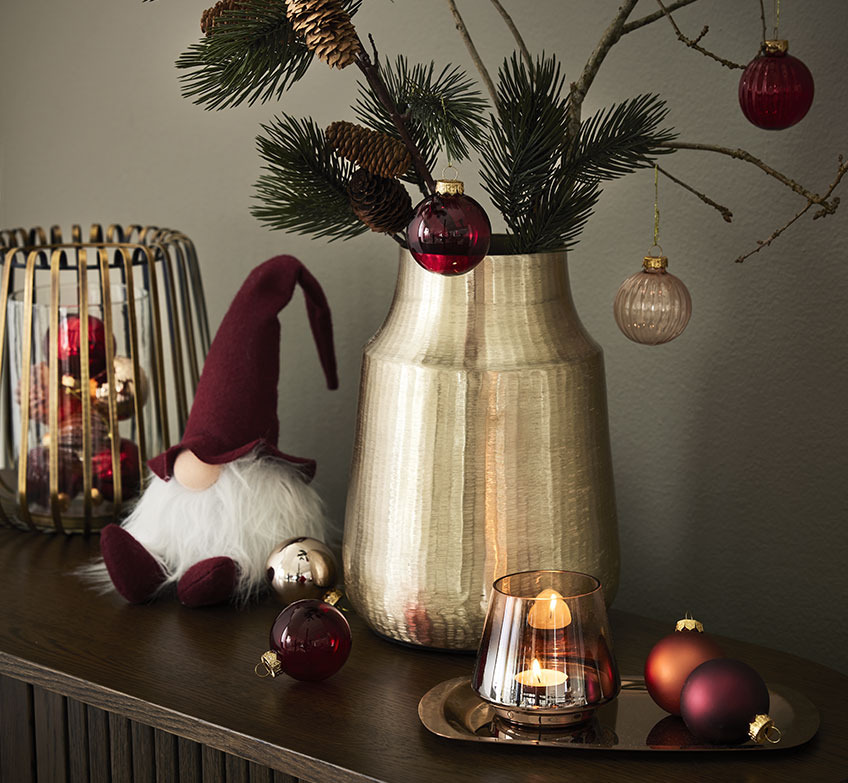 Gylden lysestage, julenisser og gylden vase med grangrene og julekugler 