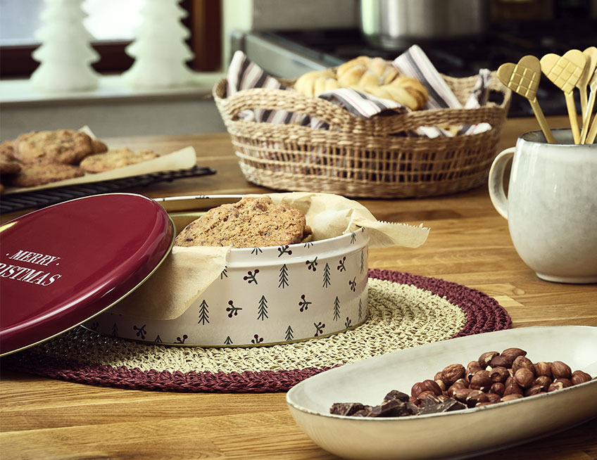 Kagedåse med småkager og fad med nødder og chokolade på køkkenbord