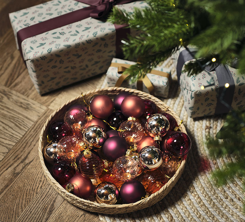 Kurv med julekugler under juletræ med gaver