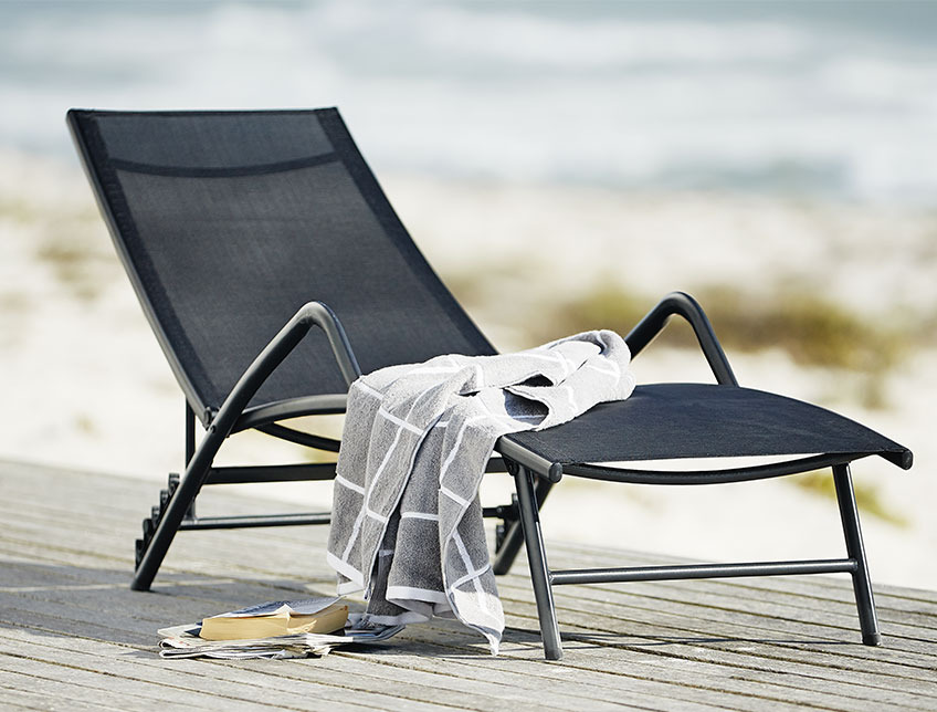 Sort liggestol med armlæn på en terrasse ved stranden