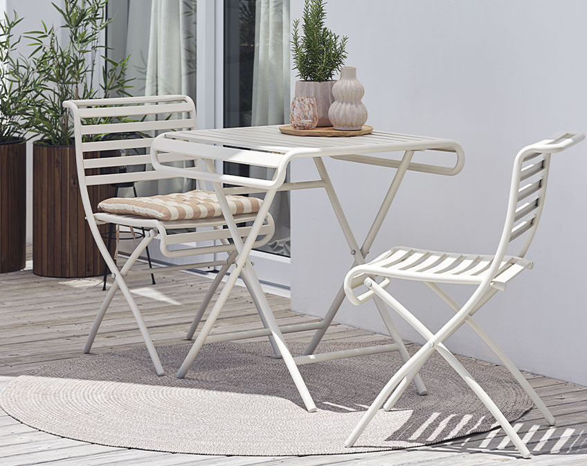 Lyst cafebord og lyse klapstole på terrasse