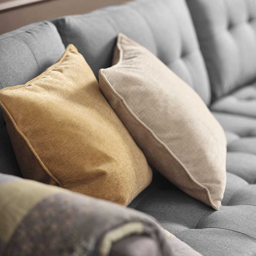 Gul og beige pyntepuder på grå sofa