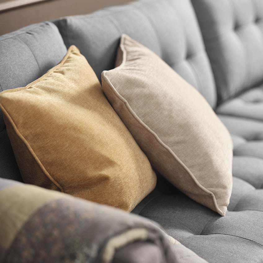 HORNFIOL pyntepuder i gul og beige Gul og beige pyntepuder på grå sofa
