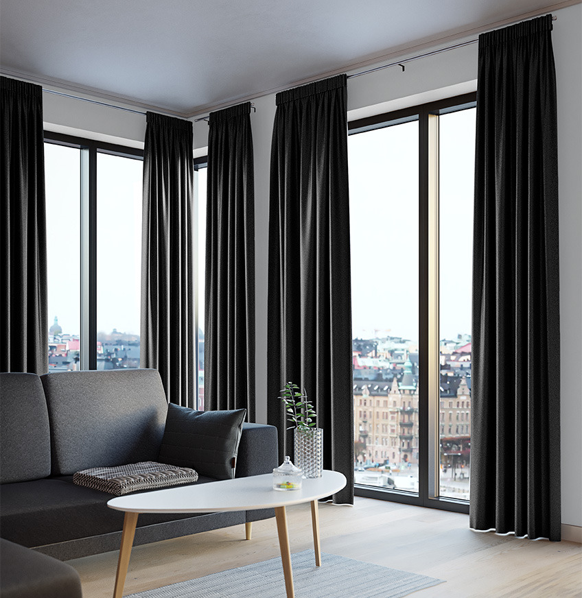 Sorte lysdæmpende gardiner ved stort vinduesparti i stue med sofa og sofabord