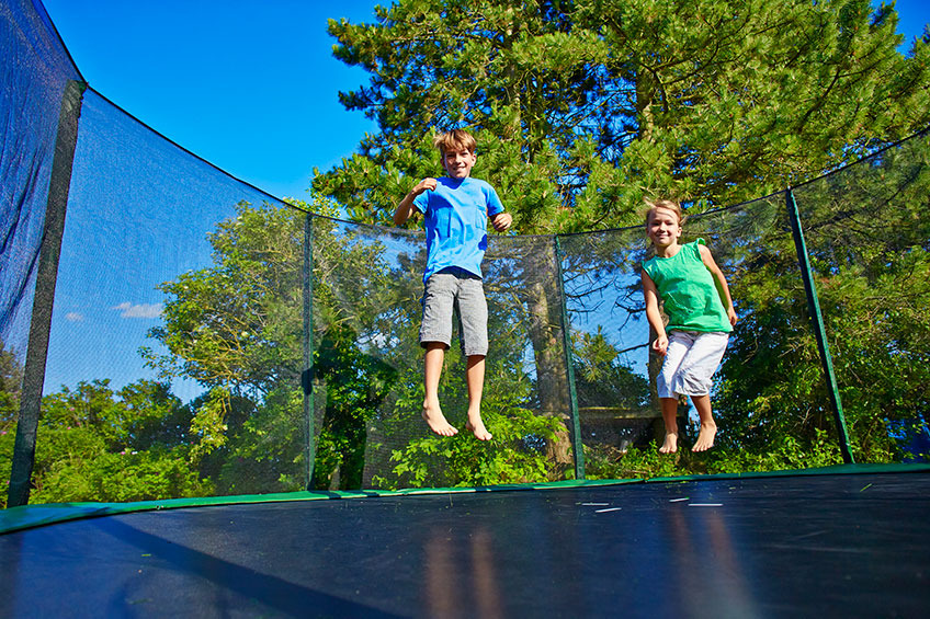 Børn der hopper på trampolin i solskinsvejr