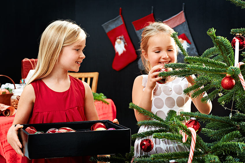 2 piger pynter juletræ med glaskugler