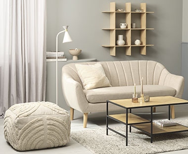 Mønstret puf, beige sofa, bambus væghylde, sofabord med hylder og hvid gulvlampe